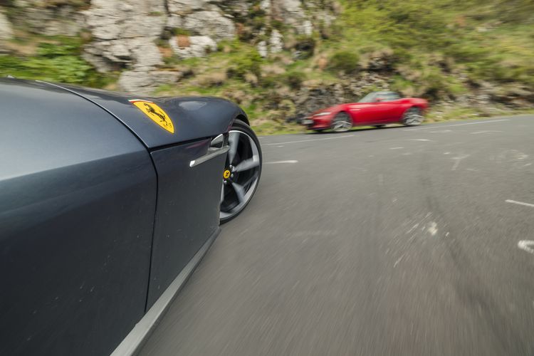 Een rode Ferrari passeert de 12Cilindri op de bergweg